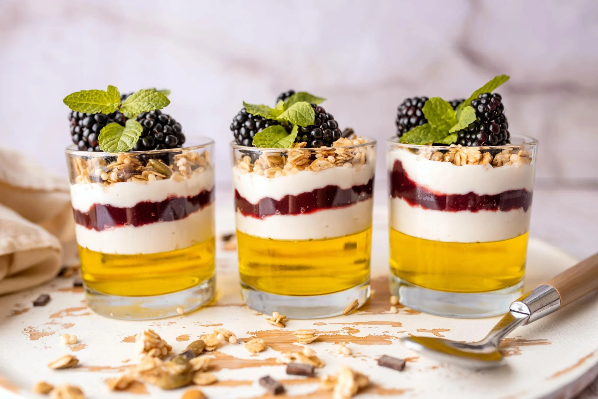 hree gelatin-containing desserts in cups and scattered nuts on the table