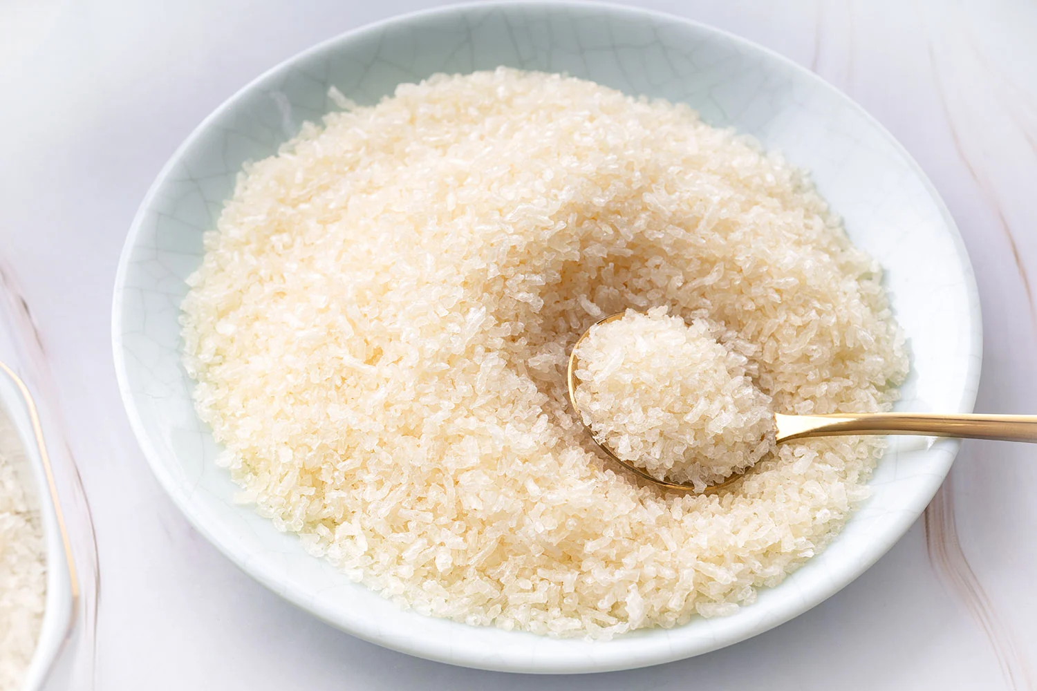 Food-grade bone gelatin granules displayed in a ceramic bowl with a gold spoon. Food-grade bone gelatin granules displayed in a ceramic bowl with a gold spoon.